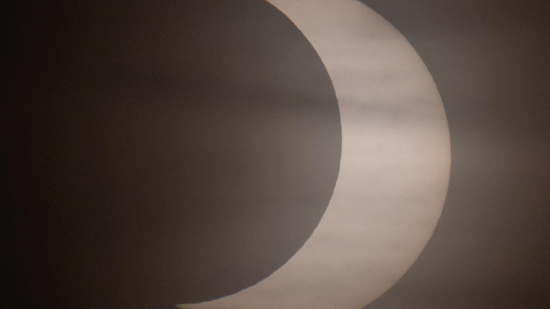 El eclipse solar parcial de este jueves, visto través de las nubes al amanecer desde la costa en Winthrop, Massachusetts, EEUU.