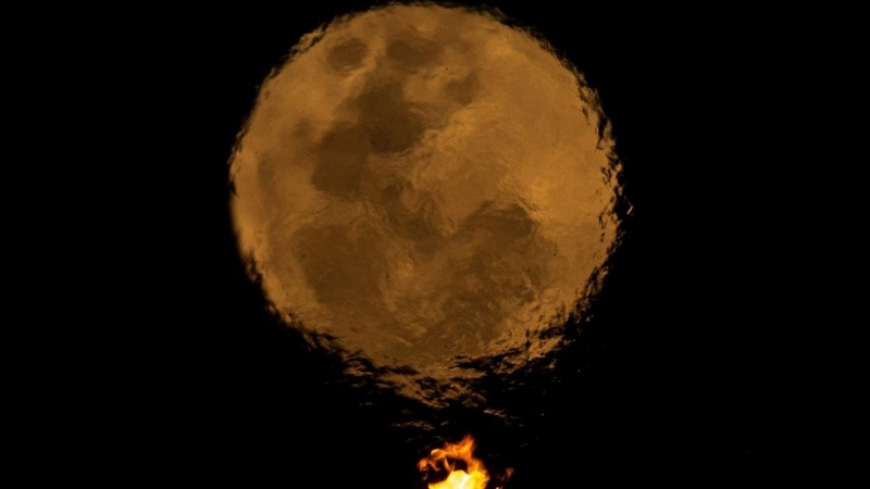 Vista de la luna llena a través de la llama del panteón de la libertad, en la ciudad de Brasilia (Brasil)