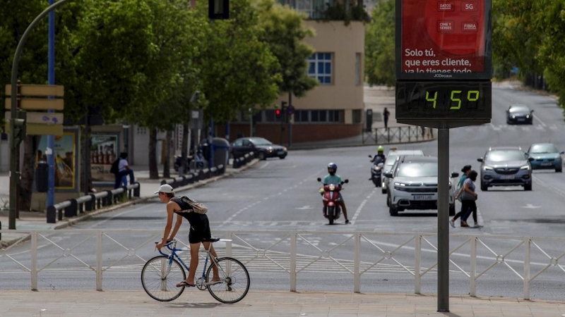Un ciclista pasa junto a un termómetro que marca 45 grados centígrados, en Sevilla. - EFE