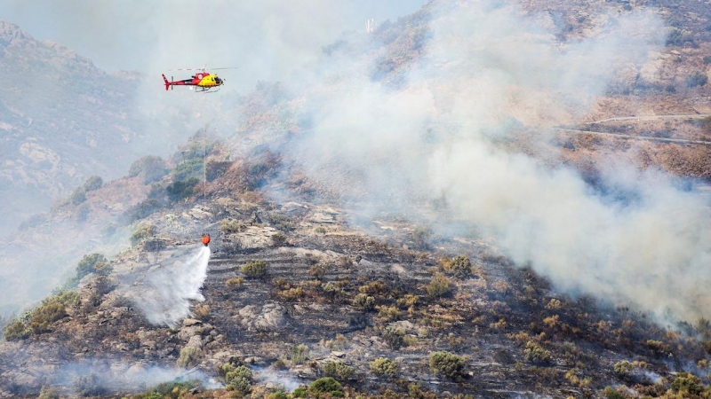 Un helicóptero realiza labores de extinción del incendio declarado en Cap de Creus, este sábado en Llançà (Girona). - EFE