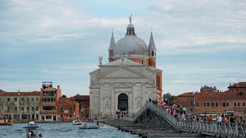 Peregrinos y turistas cruzan un puente en Venecia