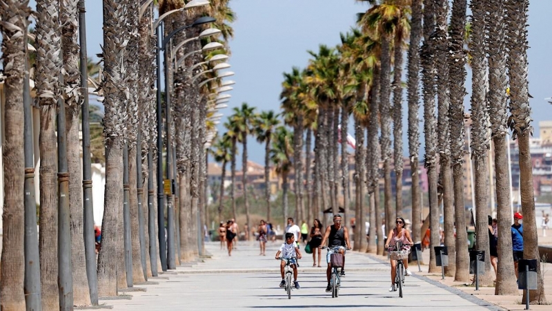 Varias personas pasean en bicicleta por el paseo de la playa de La Patacona De Alboraya (Valencia