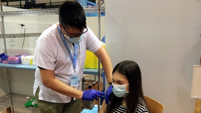 Pla mitjà d'un infermer administrant la vacuna contra la covid-19 a una jove al pavelló Onze de Setembre de Lleida, l'11 d'agost del 2021.