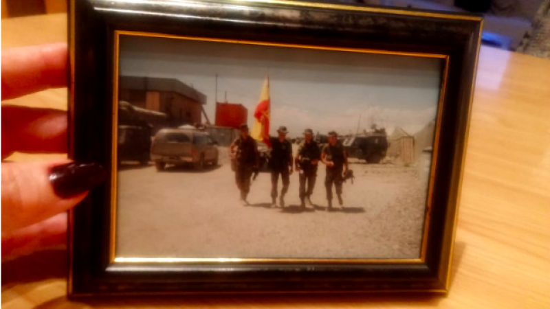 Mari Paz Fernández sostiene una foto de su marido, el comandante José Manuel Ripollés (sujetando la bandera) tomada en Afganistán antes de fallecer en acto de servicio en el siniestro del ak-42 en 2003. PÚBLICO