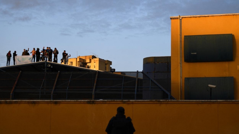 Un policía observa a un grupo de migrantes internados en el CIE de aluche pidiendo su libertad, tras ser declarado el primer confinamiento por la pandemia de covid-19, el 17 de marzo de 2020, Madrid, España.