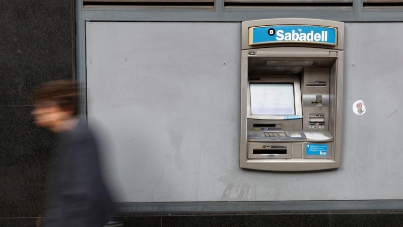 Una mujer pasa por delante de un cajero automático de una oficina del Banco Sabadell en Barcelona. REUTERS/Yves Herman