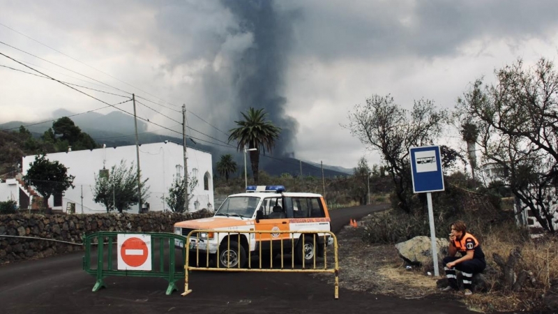 Un trabajador de Protección Civil fuma un cigarrillo mientras hace guardia para impedir el paso de vehículos y transeúntes en una carretera que lleva El Paraíso, evacuado por la cercanía del volcán.