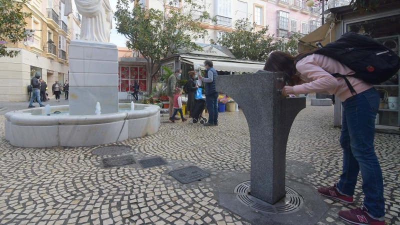 Una joven, bebiendo de una fuente pública en Cádiz.