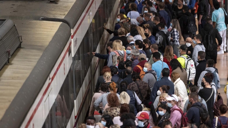 Un gran número de pasajeros espera la llegada de un tren en la estación de Madrid.