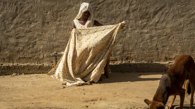 Una mujer se dispone a cortar una tela para hacerse compresas. Chad, noviembre de 2019.