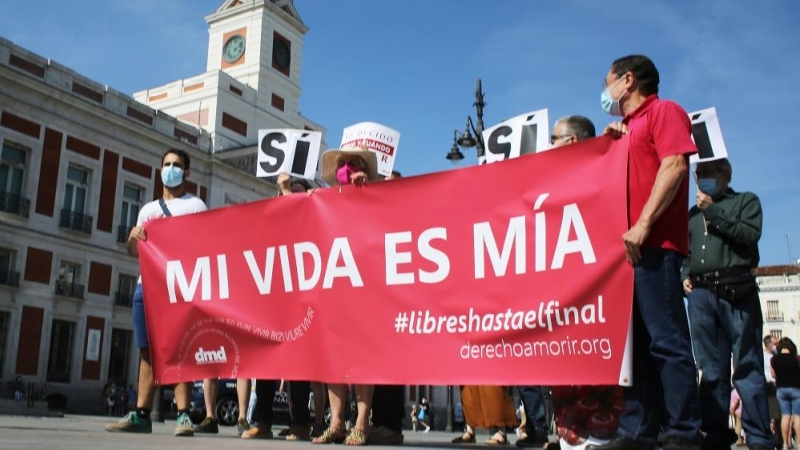 Un grupo de personas se reúne sosteniendo pancartas y carteles durante la concentración de la asociación Derecho a Morir Dignamente (DMD) en la Puerta del Sol, a 25 de junio de 2021, en Madrid, (España)