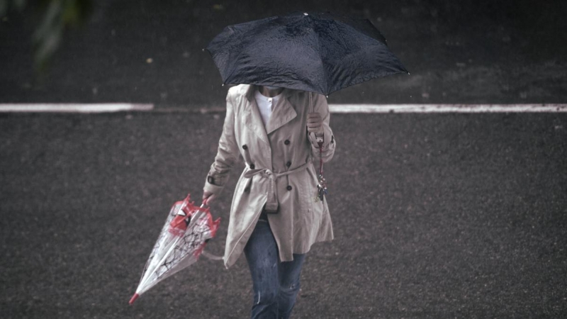 Una persona camina bajo la lluvia protegida con un paraguas, en Madrid (España).