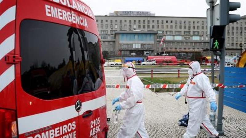 Trabajadores de la salud con trajes de protección pasan junto a una ambulancia en el nuevo centro de clasificación para pacientes con coronavirus en el Hospital Santa María, Lisboa, a 29 de enero de 2021.