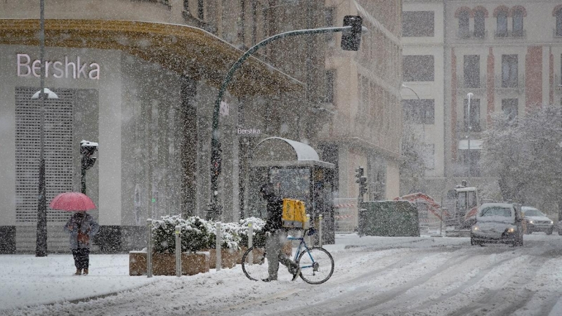 Un repartidor de comida a domicilio camina con su bicicleta por la calle Cortes de Navarra de Pamplona donde el temporal de nieve ha llegado de lleno este fin de semana.