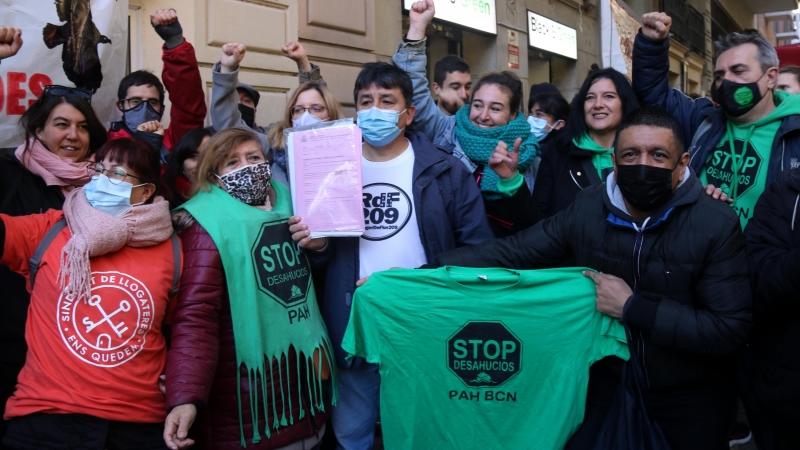 El Carlos, envoltat d'activistes pel dret a l'habitatge, mostrant el paper de suspensió del desnonament que l'afectava, aquest 3 de desembre de 2021.
