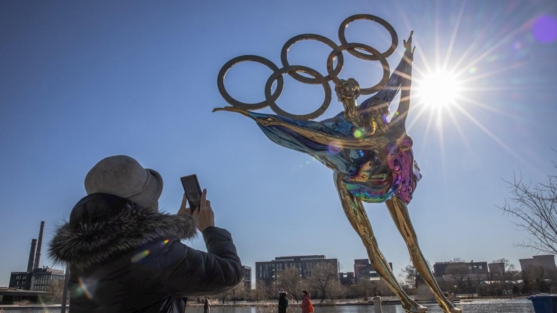 Una mujer fotografía una escultura de una pareja de patinaje artístico con motivo de los Juegos Olímpicos de Invierno 2022 en el parque industrial Shougang en Pekín.