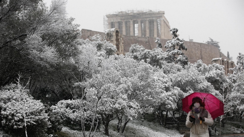 Una mujer con un paraguas pasea por la zona del Partenón, cubierto bajo un manto de nieve en Atenas (Grecia) este lunes 24 de enero de 2022.
