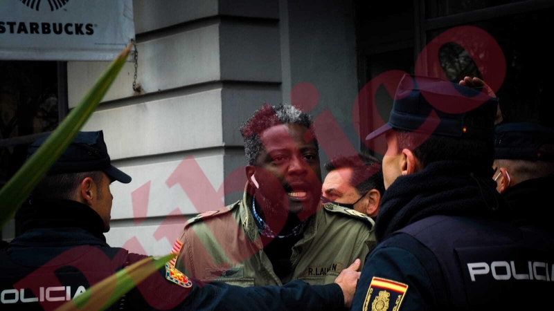 El militante de Vox Bertrand Ndongo y extrabajador del equipo de Rocío Monasterio tras un cordón de policías tras increpado en la manifestación estudiantil feminista con motivo del 8M en la Puerta del Sol de Madrid este 8 de marzo de 2022.