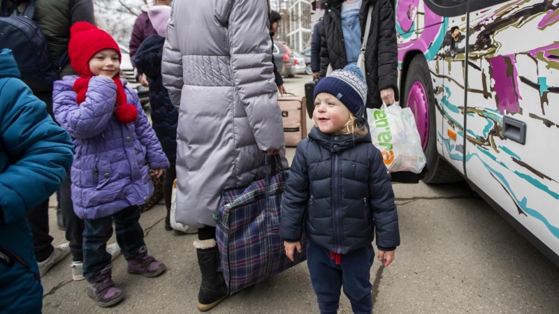 Mujeres y niños que huyen de Ucrania se preparan para tomar un autobús a Alemania, cerca de un centro de clasificación de refugiados en un estadio deportivo en Chisinau, Moldavia.