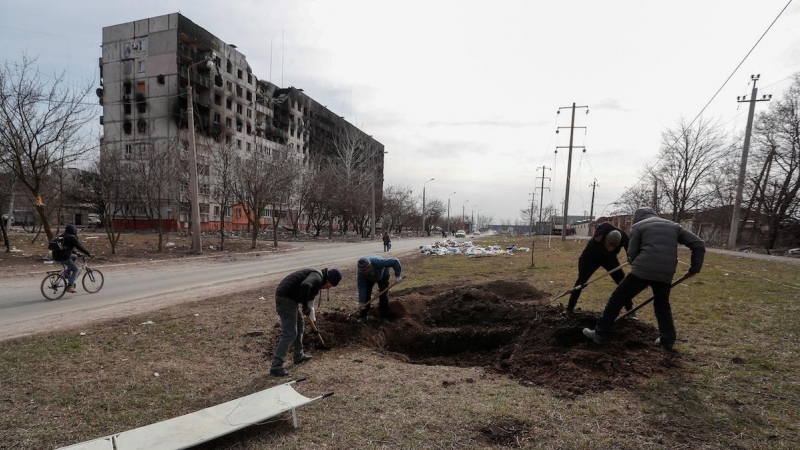 Un grupo de personas cava una tumba en una calle de la ciudad sitiada de Mariupol, Ucrania, 20 de marzo de 2022.