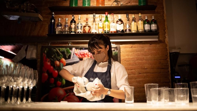 Una camarera seca unos vasos en el interior de un bar en una calle céntrica de Barcelona, a 14 de octubre de 2021, en Barcelona, Catalunya (España).