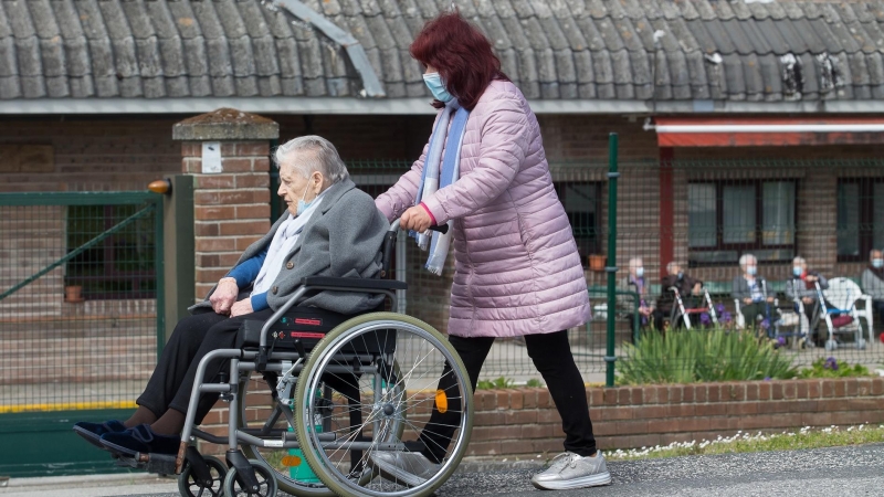 11/4/22-Una mujer pasea a una anciana en silla de ruedas, en las inmediaciones de la residencia geriátrica de As Gándaras para visitar a un familiar, a 17 de abril de 2021, en Lugo, Galicia (España).