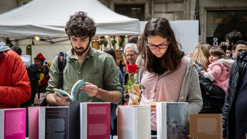 Dos personas miran libros en el día de Sant Jordi en Barcelona.