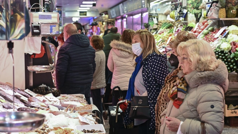 Varias clientas con y sin mascarilla aguardan a ser atendidas en un puesto de un mercado de Madrid, este miércoles.