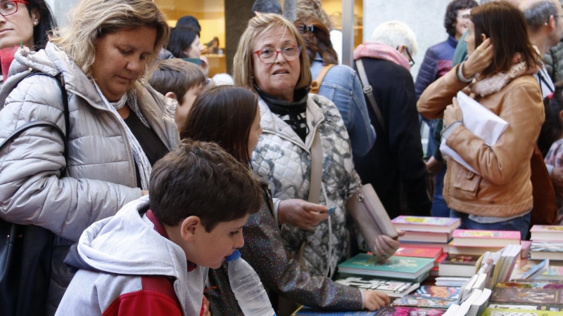 Alguns clients mirant llibres en una parada de la rambla de la Llibertat de Girona durant la diada de Sant Jordi del 2019