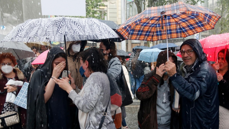 Diverses persones sota la pedregada davant les parades de llibres de Barcelona.