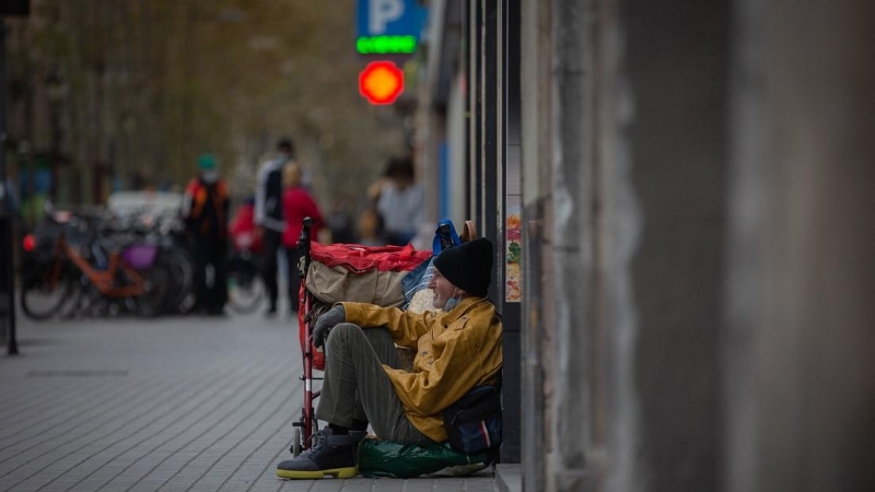 Una persona sin techo permanece en el suelo de una calle cercana al Hospital de campaña instalado en la parroquia de Santa Anna, en Barcelona, Catalunya, (España), a 14 de noviembre de 2020.