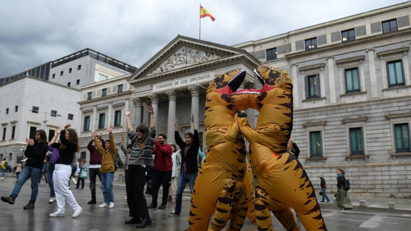Dos personas disfrazadas de dinosaurios por Ecologistas en Acción, frente al Congreso de los Diputados, a 26 de abril de 2022.