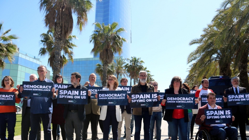 Diversos independentistes espiats per Pegasus en el 'Catalangate' mostren cartells contra l'espionatge davant de l'hotel Vela de Barcelona.