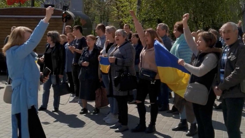 Vecinos de Jersón (Ucrania) gritan consignas y sostienen la bandera nacional de Ucrania durante una protesta en la que se les disparó gas lacrimógeno, en medio de la invasión rusa, el 27 de abril de 2022.