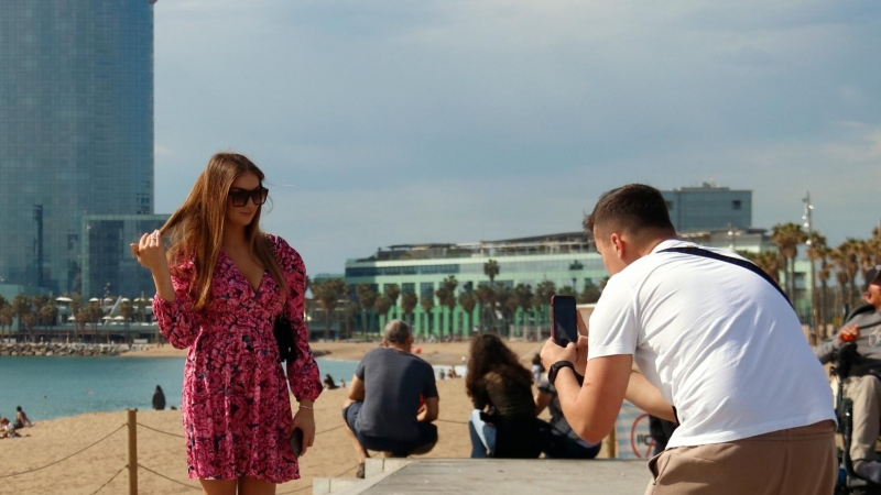 Dos turistes fent-se una foto amb l'hotel Vela de fons.
