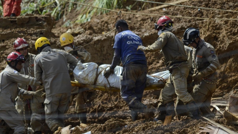 Un grupo de bomberos cargan un cuerpo rescatado tras un deslizamiento de tierras por fuertes lluvias en la ciudad de Jaboatão dos Guararapes, a 29 de mayo de 2022, en Brasil.