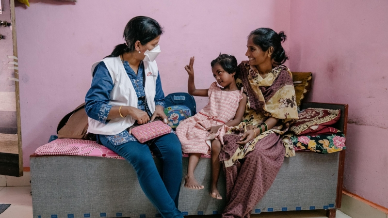 Vaishnavi, una paciente de tuberculosis resistente a los medicamentos de siete años, interactúa con una enfermera de MSF, mientras su madre la sostiene, en Mumbai.