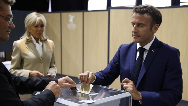 El presidente de Francia, Emmanuel Macron (R), emite su voto seguido por su esposa, la primera dama francesa Brigitte Macron (C), en las elecciones parlamentarias francesas en un colegio electoral en Le Touquet, en el norte de Francia, el 12 de junio de 2