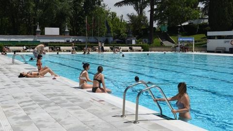 Varias personas se bañan y toman el sol, en la piscina municipal de Casa de Campo, a 14 de mayo de 2022, en Madrid (España).