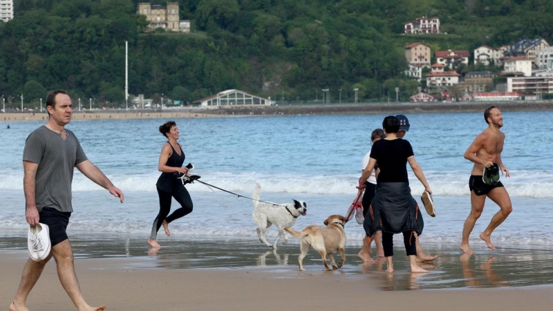 Varias persona caminan y corren con perros en la playa de La Concha en mayo de 2020 (Archivo).