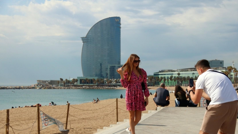 08/05/2022 - Dos turistes fent-se una foto a la Barcelona, amb l'hotel W de fons.