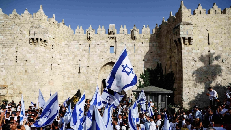 Los israelíes bailan y cantan mientras sostienen banderas nacionales israelíes junto a la puerta de Damasco en la ciudad vieja de Jerusalén.