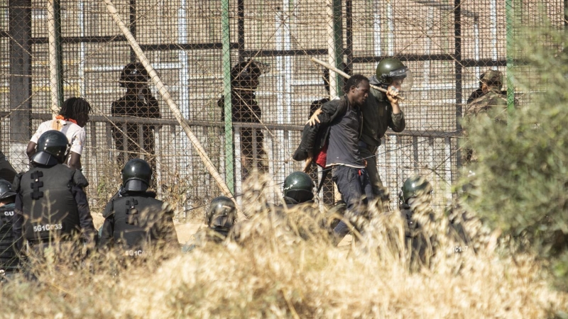 Un miembro de las fuerzas de seguridad marroquíes conduce desde suelo español a uno de los migrantes que logró saltar la valla de Melilla el pasado viernes.