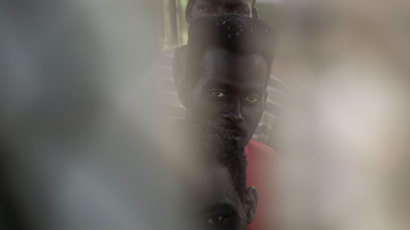 Tres de los migrantes que lograron cruzar a Melilla el pasado viernes, visto por una rendija en el Centro de Estancia Temporal para Migrantes (CETI), donde están en en cuarentena.