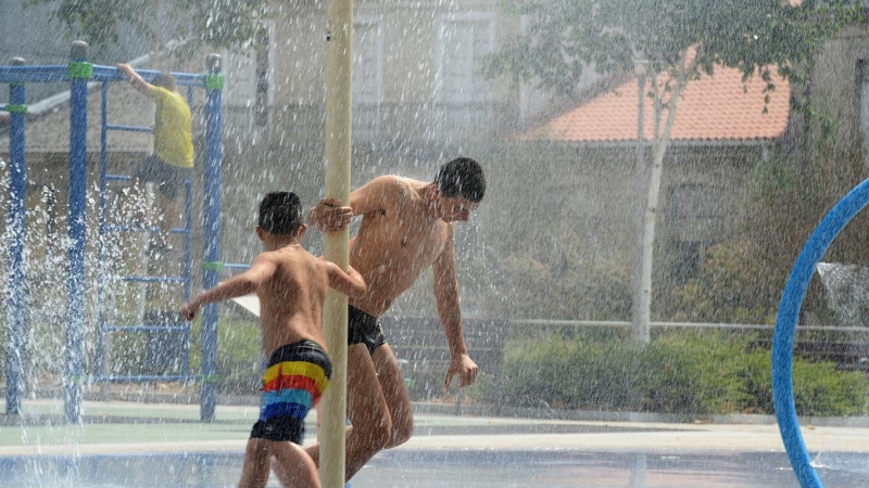 (14/7/2022) Dos jóvenes se refrescan en unos chorros durante un día de la segunda ola de calor de verano en España, a 14 de julio de 2022, en Ourense.