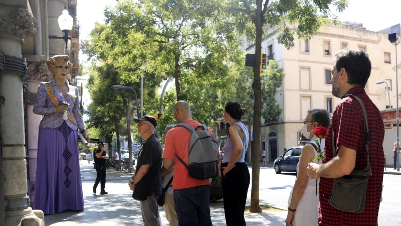 Un home espera amb una rosa per entrar a la capella ardent de Núria Feliu i observa la geganta de l'artista, a les portes del districte de Sants-Montjuïc, a Barcelona.