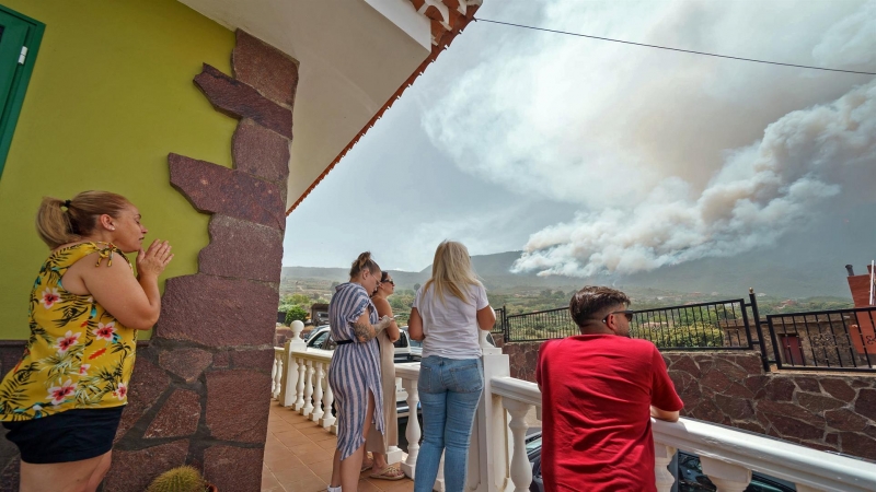 Vecinos del barrio de Las Llanadas, en el municipio tinerfeño de Los Realejos, observan el incendio que afecta al norte de la isla.