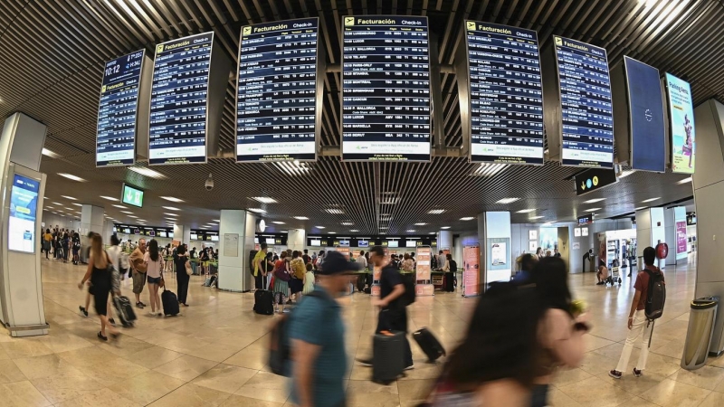 Varios pasajeros pasan por las pantallas de información en el aeropuerto Adolfo Suárez Madrid-Barajas, a 25 de julio de 2022.