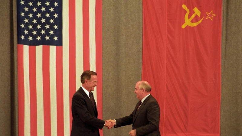 El presidente estadounidense George H. W. Bush (izq.) y el presidente soviético Mijáil Gorbachov se dan la mano frente a las banderas estadounidenses y soviéticas, tras un encuentro en Moscú el 31 de julio de 1991. REUTERS/Rick Wilking