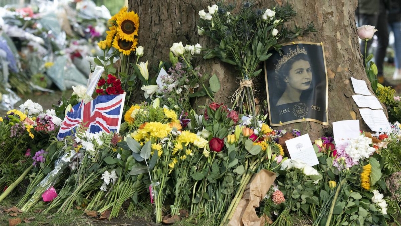 La imagen de la reina yace junto a flores y banderas en su memoria.